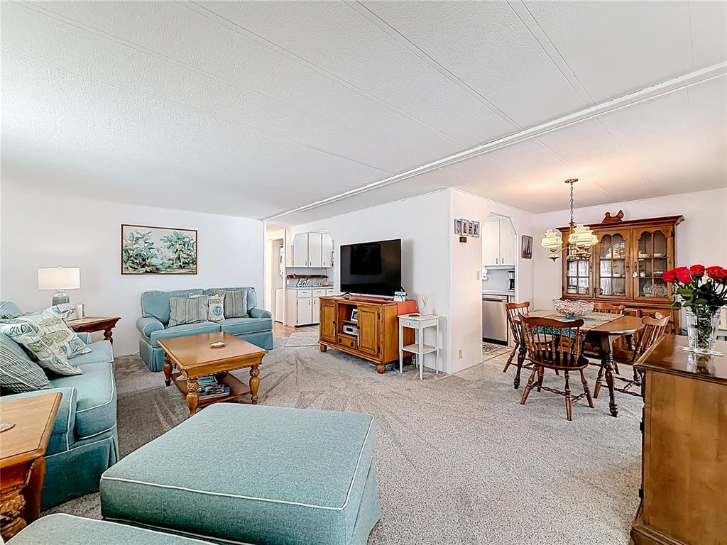 A living room and dining area feature light carpeting, blue furniture, and a wooden hutch — 665 54TH STREET S UNIT 133, GULFPORT, FL