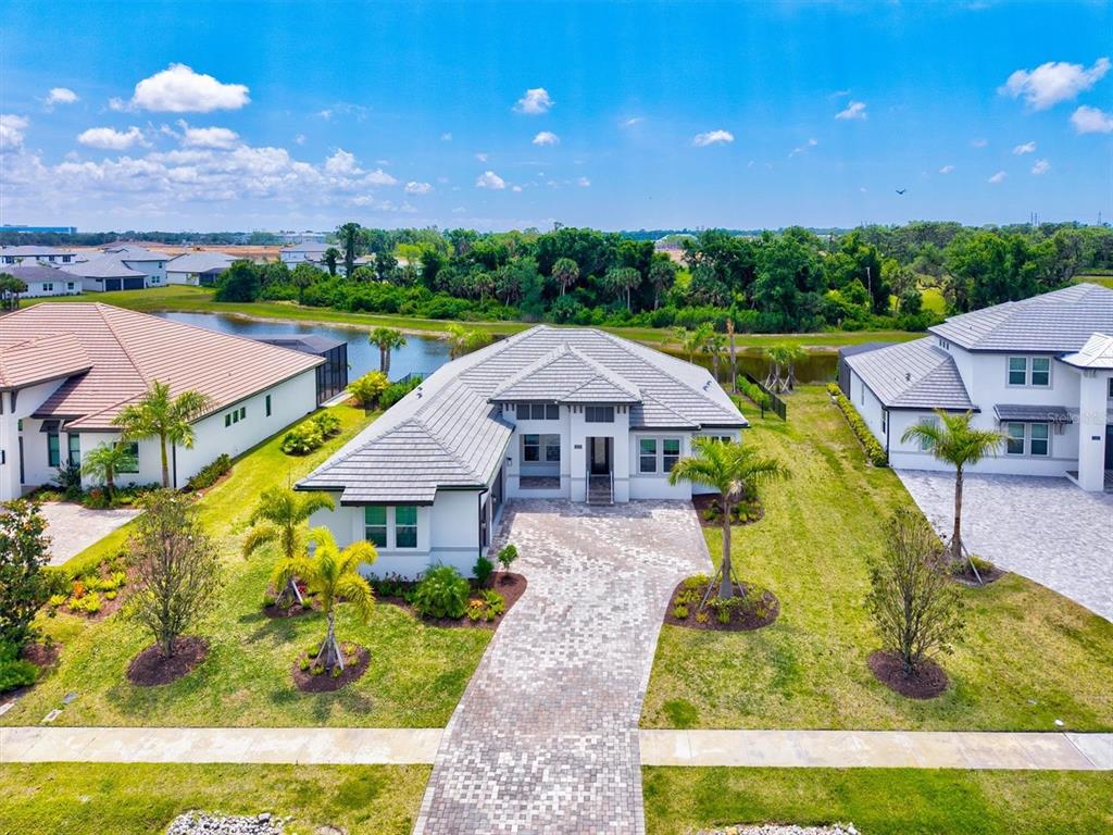 An aerial view of a single-story house with a paver driveway and a backyard pond — 1154 KINGS WAY DRIVE, NOKOMIS, FL
