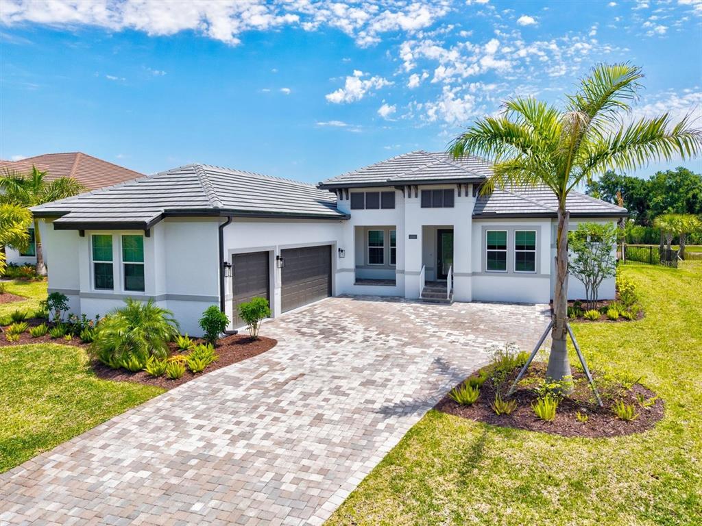A single-story house with a gray tile roof, white stucco exterior, and a paver driveway — 1154 KINGS WAY DRIVE, NOKOMIS, FL