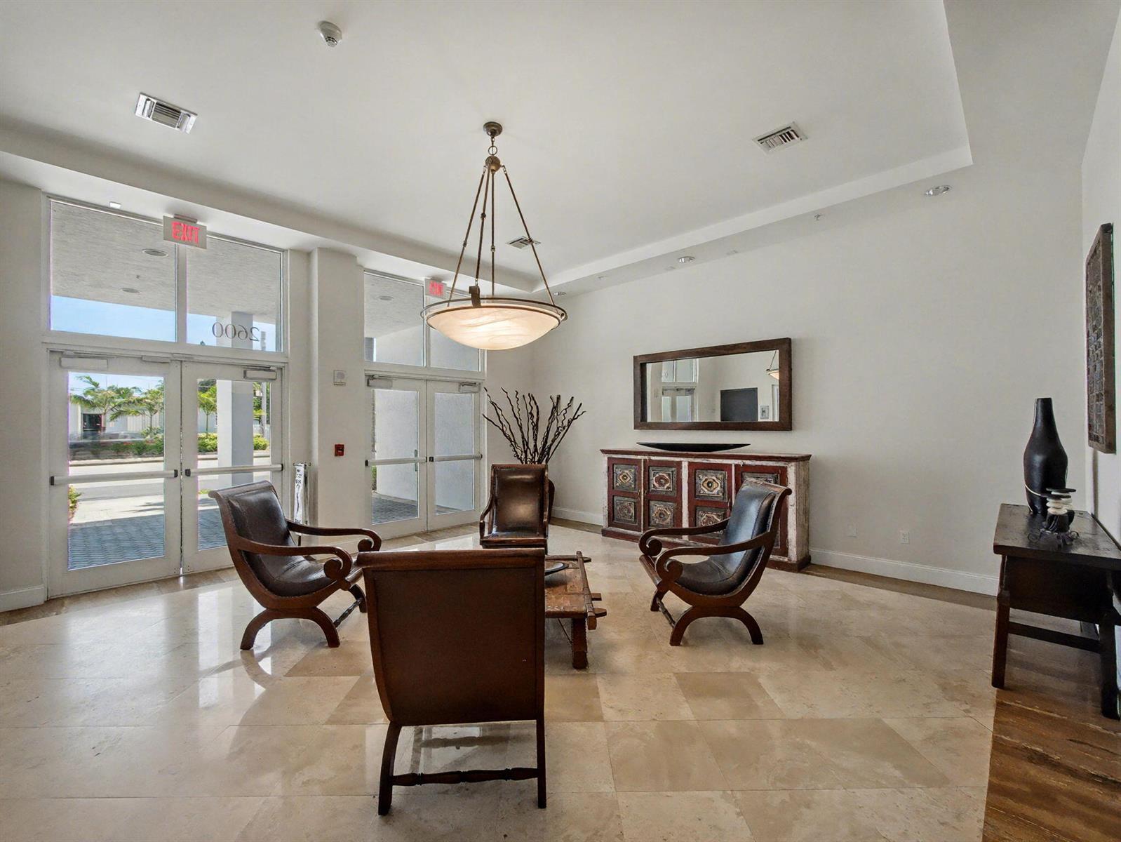 A bright lobby features four leather chairs, a wooden console table, and marble tile flooring — 2600 SW 27th Avenue # 603, Miami FL 33133, MIAMI, FL