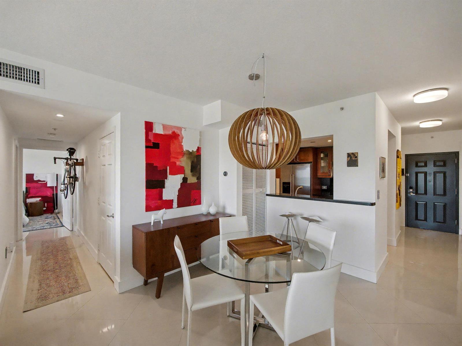 A dining area with a glass table, white chairs, and a wooden pendant light fixture — 2600 SW 27th Avenue # 603, Miami FL 33133, MIAMI, FL