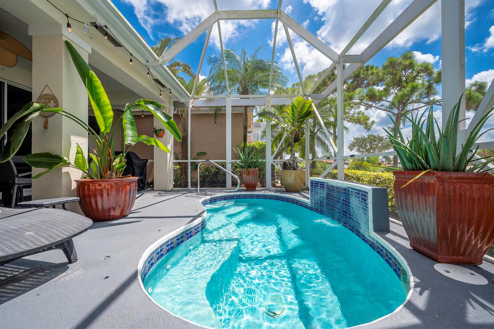 A screened-in patio features a small swimming pool with a tiled water feature and plants — 8193 Sandpiper Way, West Palm Beach FL 33412, WEST PALM BEACH, FL