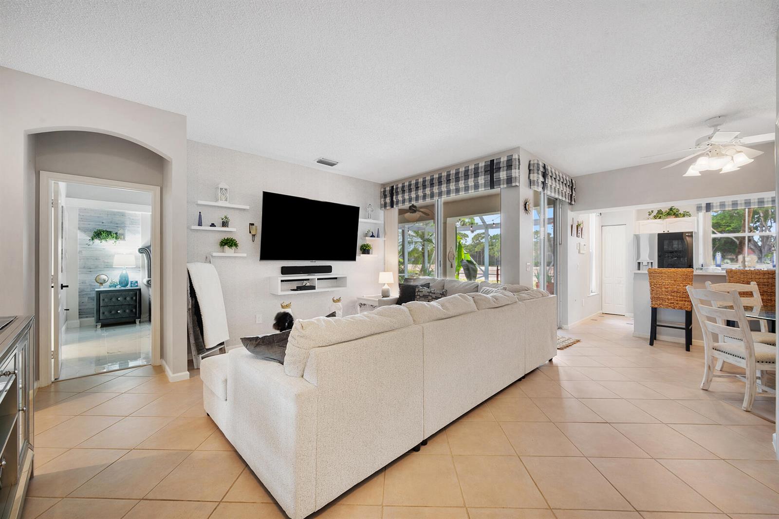 A living room features a large sectional sofa, a wall-mounted television, and tile flooring — 8193 Sandpiper Way, West Palm Beach FL 33412, WEST PALM BEACH, FL