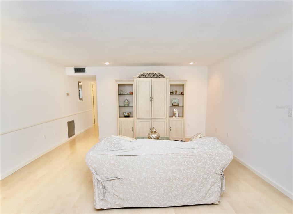 This AI-generated rendering shows a living room and dining area with neutral furniture and decor — 1713 BELLEAIR FOREST DRIVE UNIT C, BELLEAIR, FL