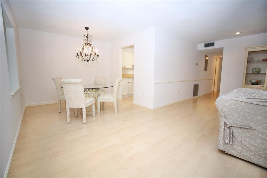 A galley kitchen with white cabinets, light wood countertops, and a view into a dining area — 1713 BELLEAIR FOREST DRIVE UNIT C, BELLEAIR, FL