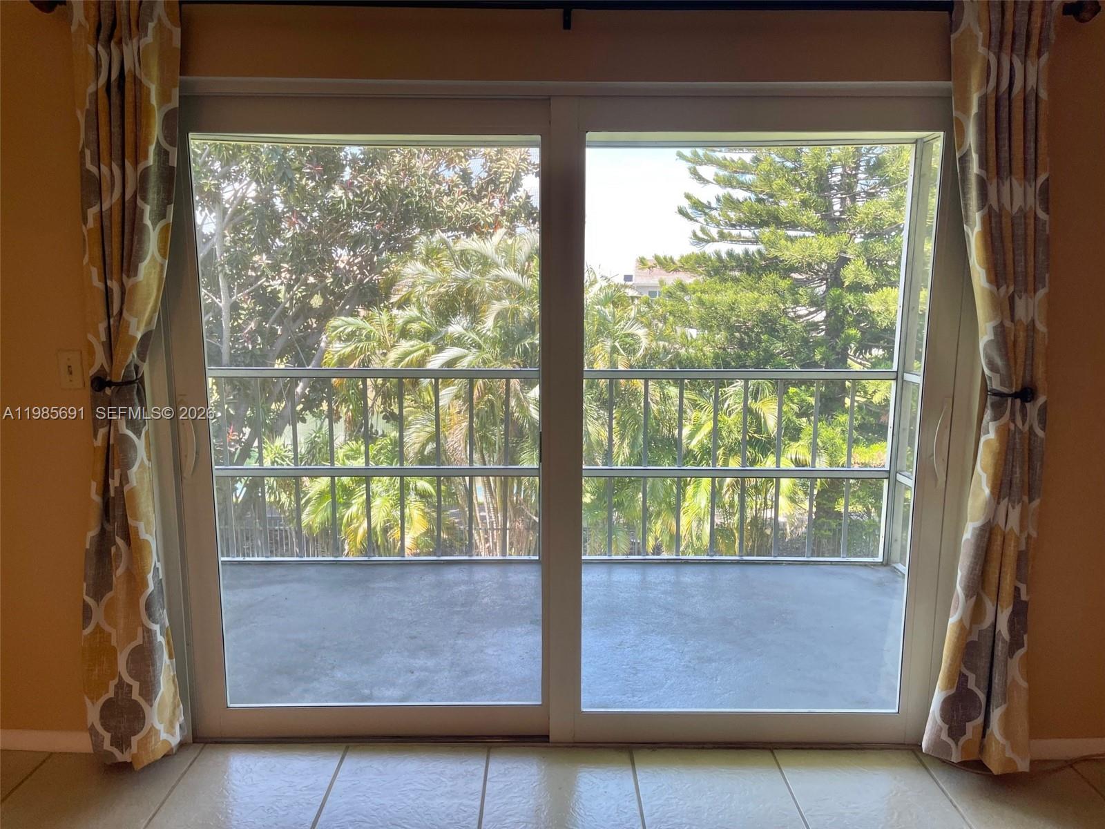 A sliding glass door opens onto a balcony overlooking trees and a metal railing — 1000 Hillcrest Ct # 308, Hollywood FL 33021, HOLLYWOOD, FL