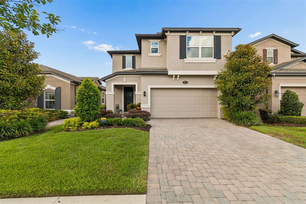 A two-story suburban house with a beige stucco exterior, a paved driveway, and landscaped lawn — 19948 STONE PINE CIRCLE, LUTZ, FL