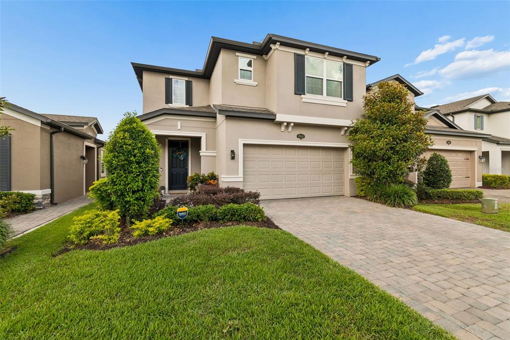 A two-story suburban house with a beige stucco exterior, a two-car garage, and a driveway — 19948 STONE PINE CIRCLE, LUTZ, FL