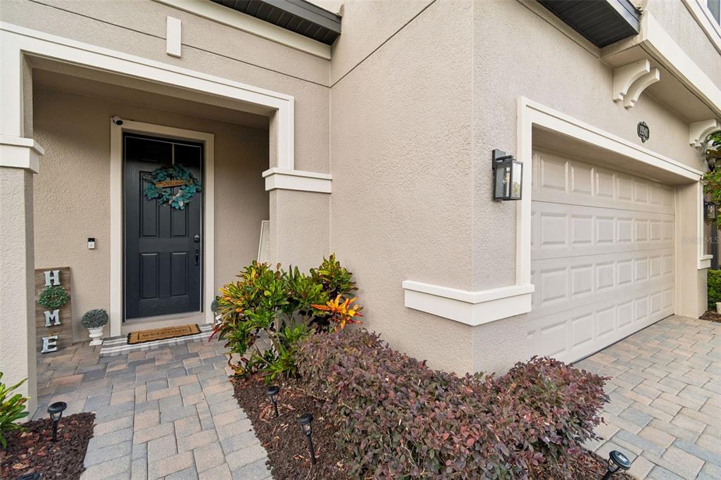 The exterior of a house features a dark front door, a garage, and landscaped bushes — 19948 STONE PINE CIRCLE, LUTZ, FL