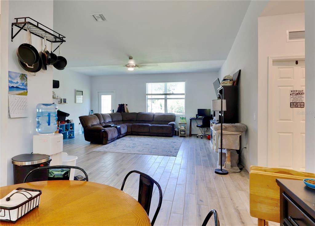 A spacious living room features light wood-look flooring, a large sectional sofa, and a ceiling fan — 22437 ADORN AVENUE, PORT CHARLOTTE, FL