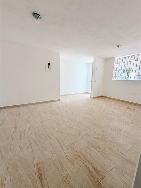 An empty room with light-colored tile flooring, white walls, and a window with security bars — Calle 601 BLOQUE 224 COMERCIAL 2, CAROLINA, PR