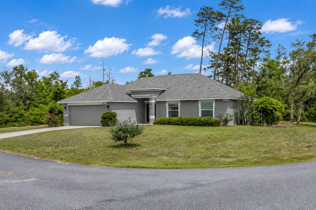 A gray single-story house with a two-car garage sits on a grassy lot — 15947 SW 26TH COURT, OCALA, FL