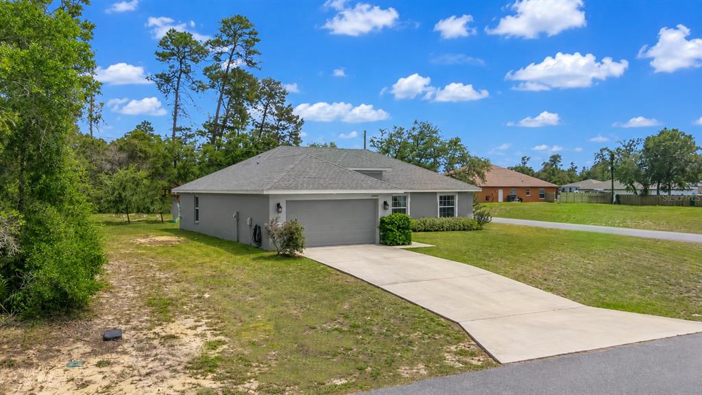 A single-story house with a gray garage, concrete driveway, and a hip roof — 15947 SW 26TH COURT, OCALA, FL