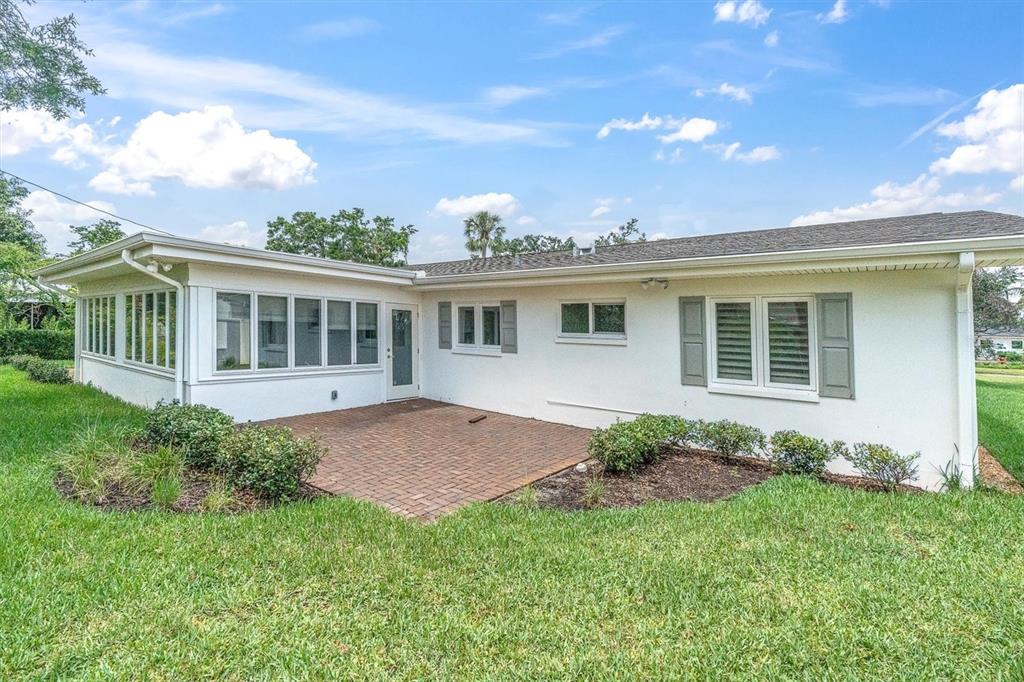 The exterior of a white house features a brick patio and a sunroom — 319 RAFAEL BOULEVARD NE, ST PETERSBURG, FL