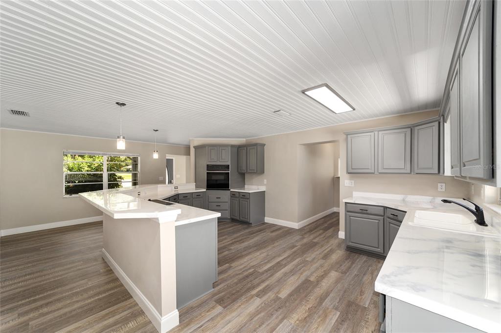 A kitchen with gray cabinets, white countertops, and wood-look flooring under a paneled ceiling — 3612 SE 34TH COURT, OCALA, FL