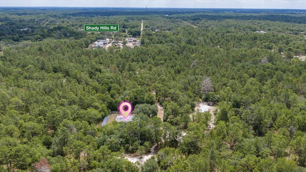 An aerial view shows a small building and a tall antenna tower surrounded by forest — 15624 PEACE BOULEVARD, SPRING HILL, FL