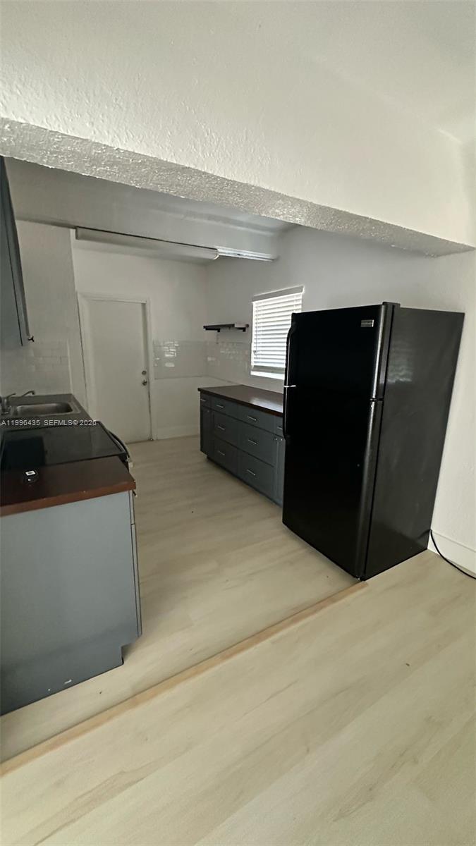 A kitchen features grey cabinets, dark wood countertops, and a black refrigerator — 715 SW 6th St, Dania Beach FL 33004, DANIA BEACH, FL