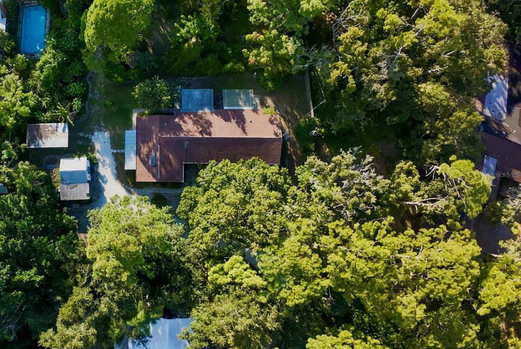 An aerial view shows a house with a brown roof surrounded by dense trees — 550 46TH STREET, SARASOTA, FL