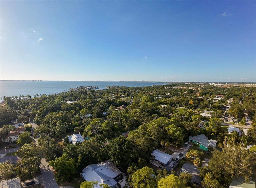 An aerial view shows a coastal neighborhood with many trees and houses near the water — 550 46TH STREET, SARASOTA, FL