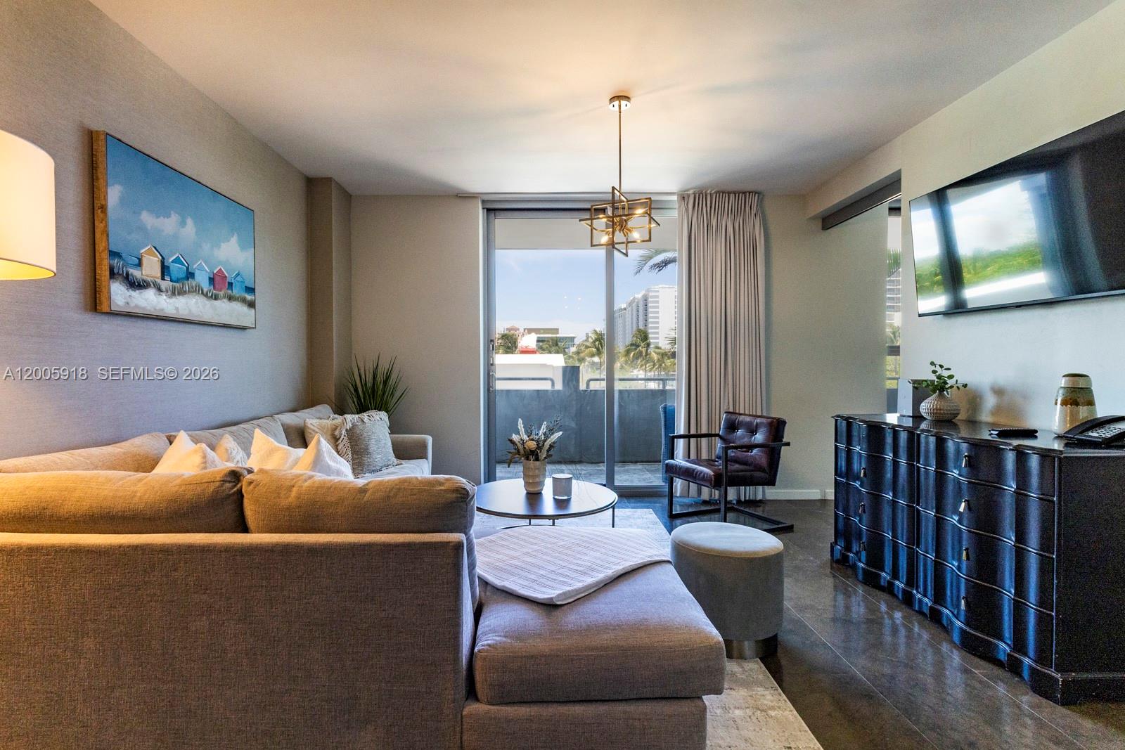 A living room features a grey sectional sofa, a dark dresser, and a balcony view — 220 21st St # 303, Miami Beach FL 33139, MIAMI BEACH, FL