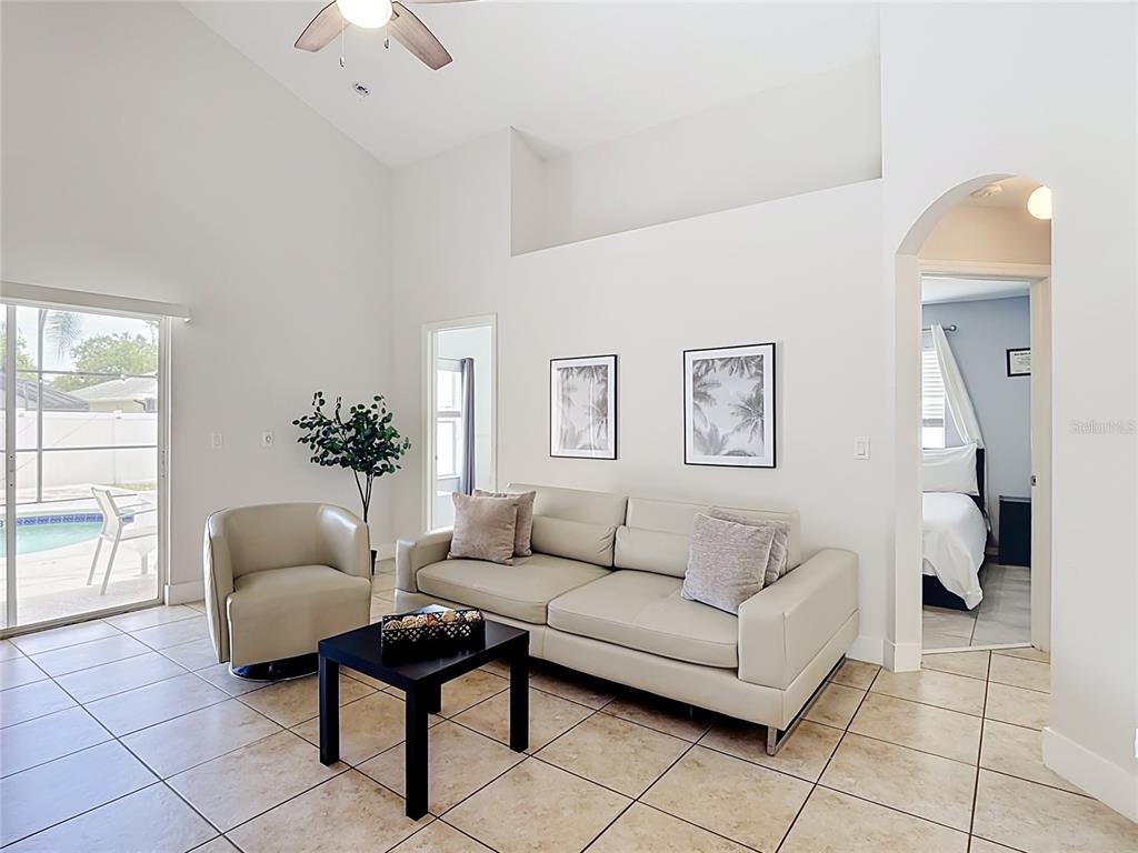 A living room features tile floors, a vaulted ceiling, a sofa, and a sliding glass door — 1021 TOURMALINE DRIVE, KISSIMMEE, FL