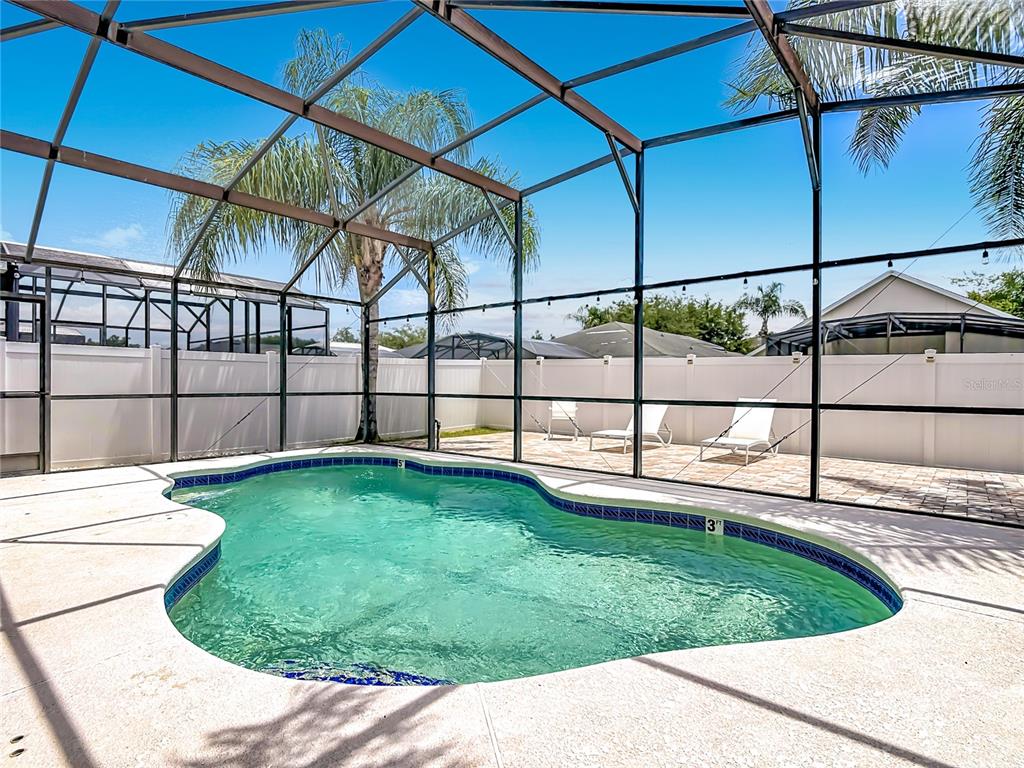 A screened-in swimming pool with a patio and white vinyl fencing in a backyard — 1021 TOURMALINE DRIVE, KISSIMMEE, FL