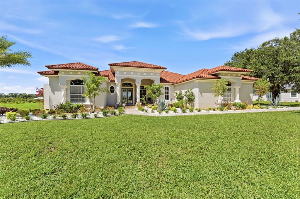 A single-story house with a red tile roof and a large front lawn — 24355 HIDEOUT TRAIL, LAND O LAKES, FL