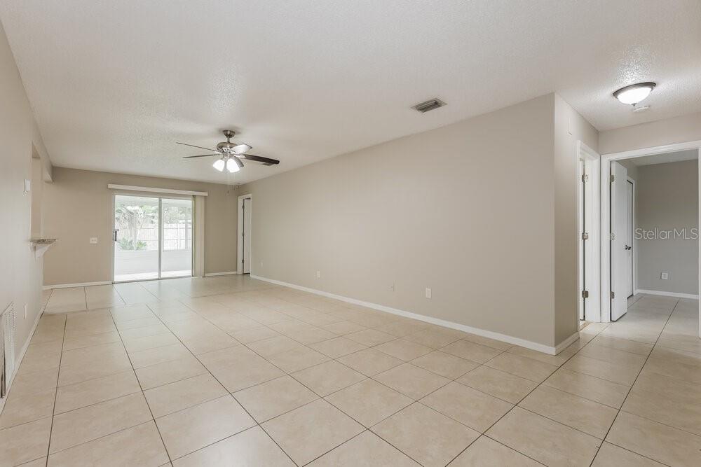An empty living room with beige tile flooring, neutral walls, and a ceiling fan — 12438 DAWN VISTA DRIVE, RIVERVIEW, FL