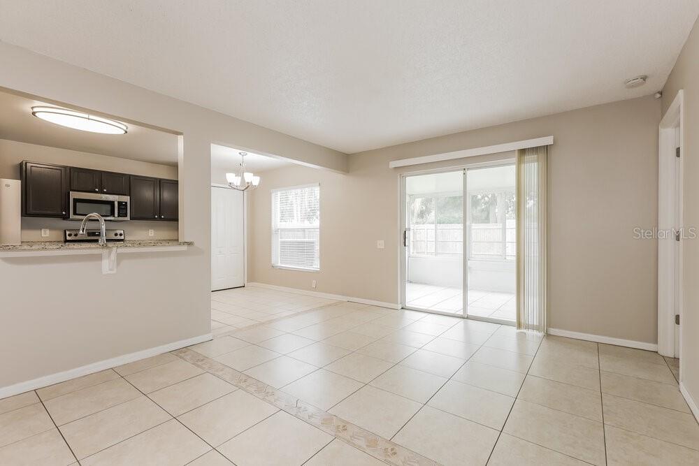 An open-concept living and dining area features light tile flooring and a sliding glass door — 12438 DAWN VISTA DRIVE, RIVERVIEW, FL