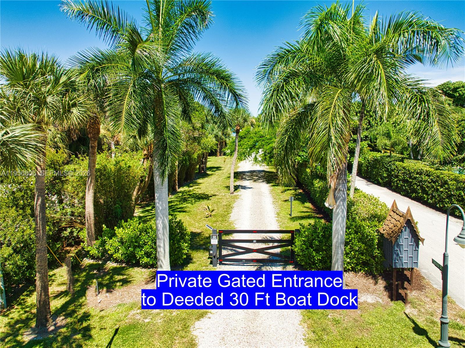 A gravel driveway leads to a gated entrance flanked by palm trees and lush landscaping — 123 S Sewalls Point Rd, Sewalls Point FL 34996, SEWALLS POINT, FL