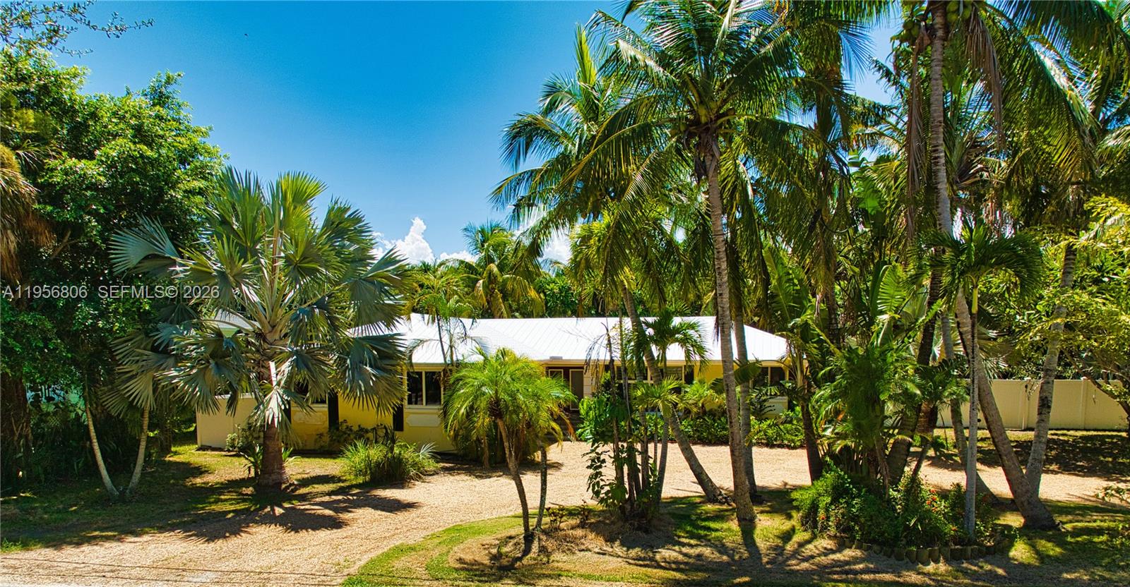 A single-story house with a white roof is surrounded by palm trees and gravel landscaping — 123 S Sewalls Point Rd, Sewalls Point FL 34996, SEWALLS POINT, FL