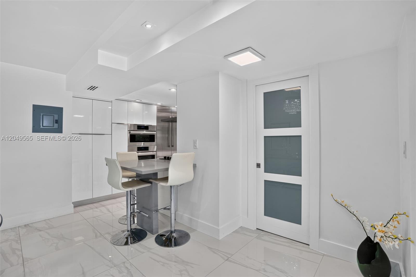A modern kitchen features white cabinetry, stainless steel appliances, and a marble-tiled floor — 6039 Collins Ave # 1624, Miami Beach FL 33140, MIAMI BEACH, FL