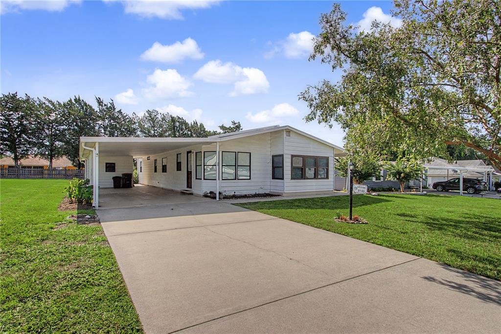 A white single-wide mobile home with a carport sits on a grassy lot — 8145 SW 64TH AVENUE, OCALA, FL