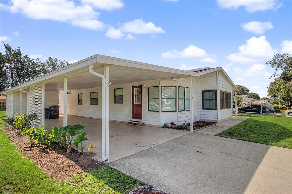 A white mobile home with a red front door, a carport, and a concrete porch — 8145 SW 64TH AVENUE, OCALA, FL