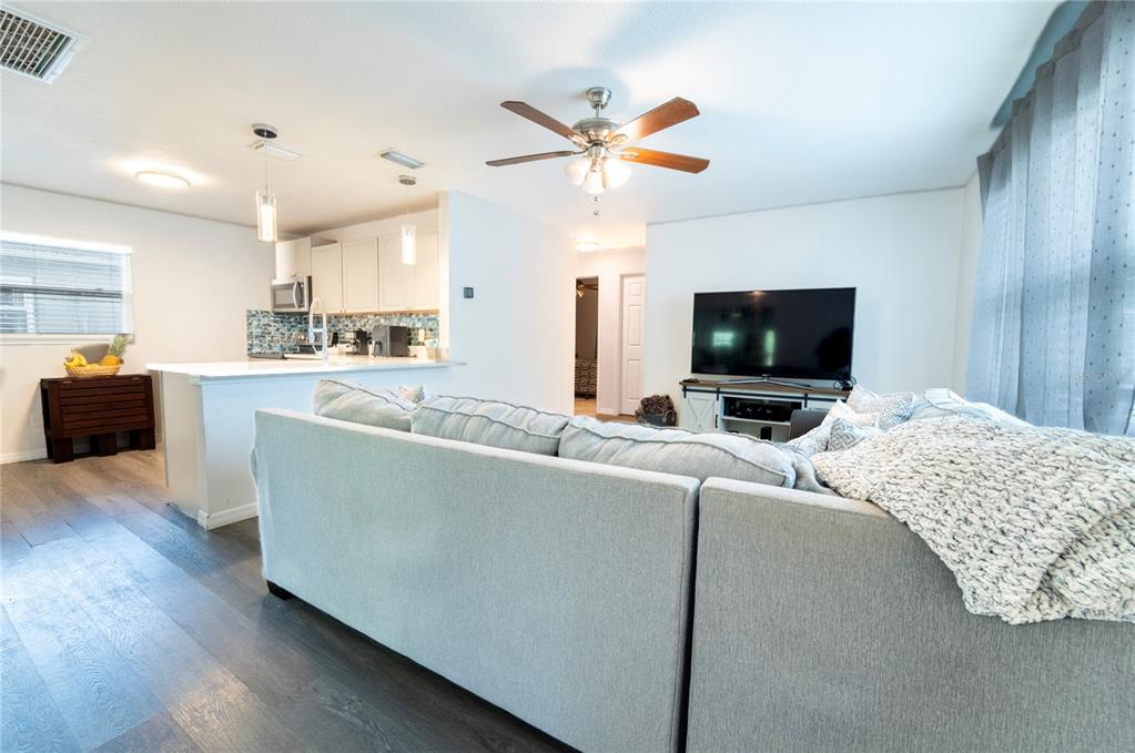 A kitchen features white cabinets, a large quartz island with a sink, and a backsplash — 7407 MOUNT VERNON ROAD, TAMPA, FL
