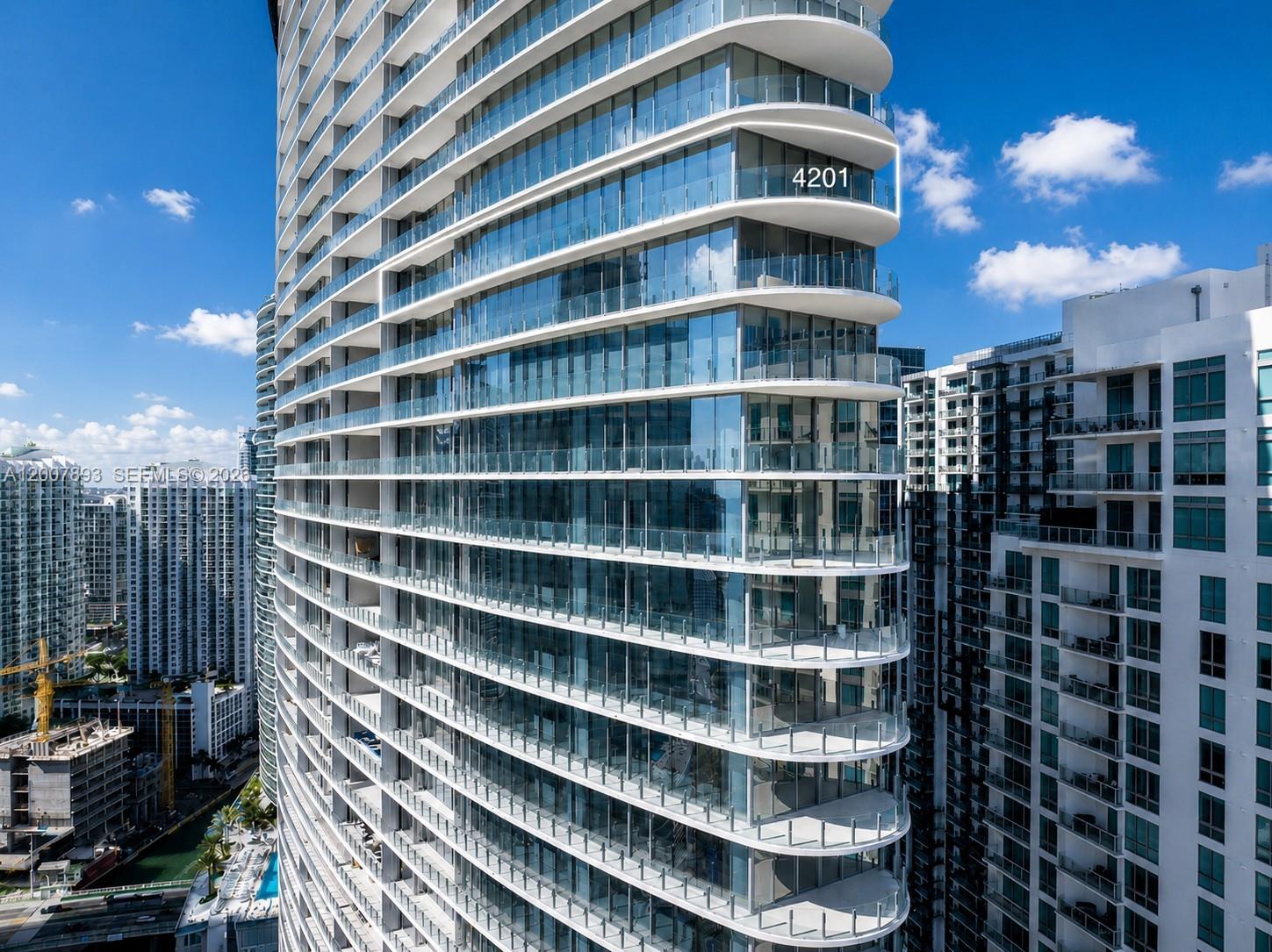 An exterior view of a modern high-rise residential building with curved glass balconies — 300 Biscayne Boulevard Way # 4201E, Miami FL 33131, MIAMI, FL