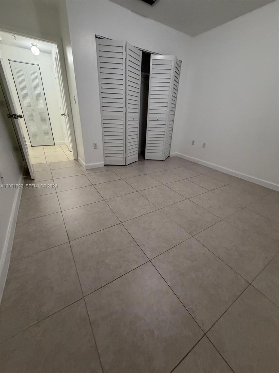 This room features light-colored floor tiles, white walls, and a white louvered closet door — 1300 NE 109th St # 404, Miami FL 33161, MIAMI, FL