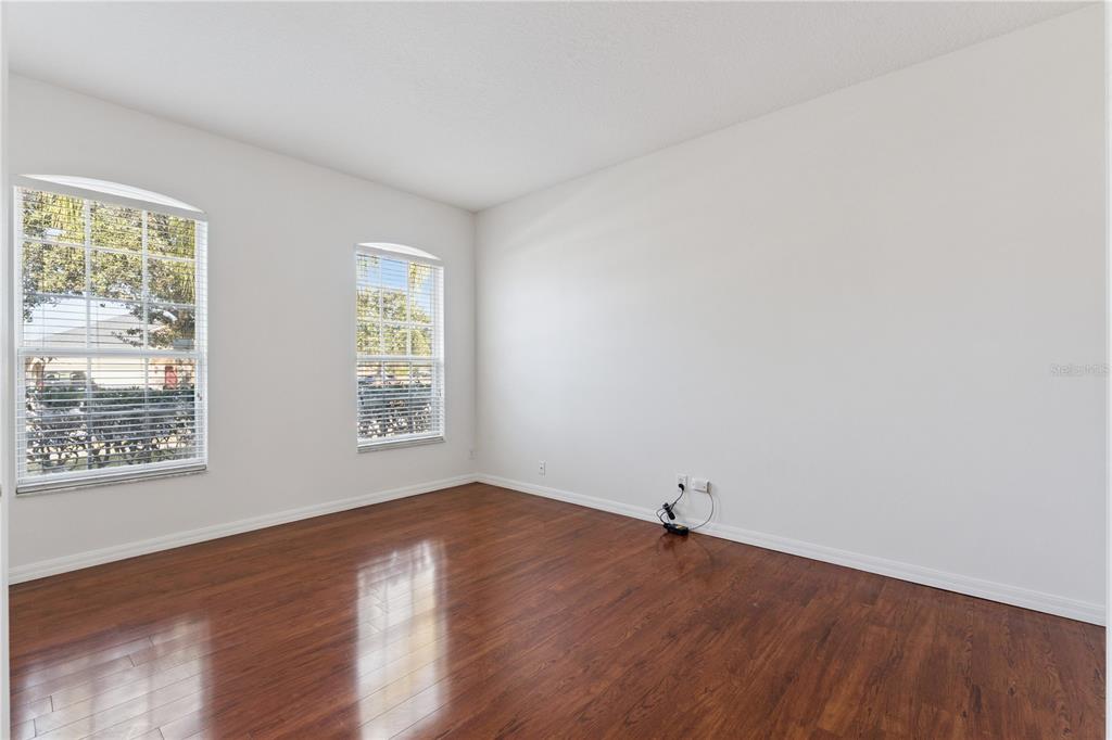 An empty room with white walls, two arched windows, and dark wood-look flooring — 5295 ADAIR OAK DRIVE, ORLANDO, FL