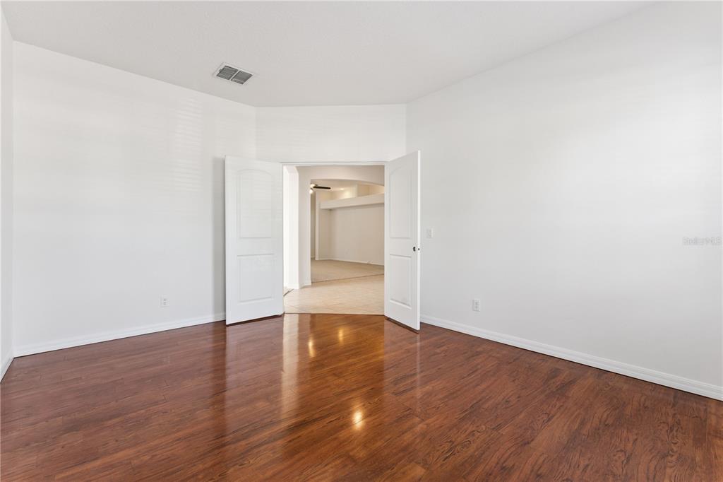 An empty room with white walls, dark wood flooring, and open double doors — 5295 ADAIR OAK DRIVE, ORLANDO, FL