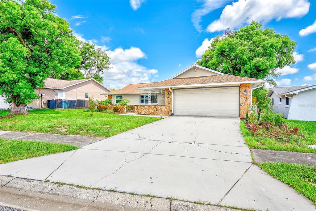 A single-story house with a stone facade, a two-car garage, and a concrete driveway — 8741 HONEYCOMB DRIVE, PORT RICHEY, FL