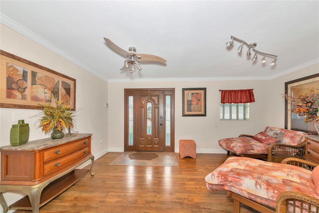 An entryway with wood flooring, a wooden front door, a ceiling fan, and lounge furniture — 509 RIDGEWOOD STREET NW, PORT CHARLOTTE, FL