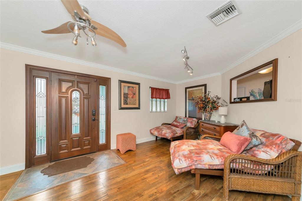 An entryway with a wooden front door, hardwood floors, and two wicker lounge chairs — 509 RIDGEWOOD STREET NW, PORT CHARLOTTE, FL
