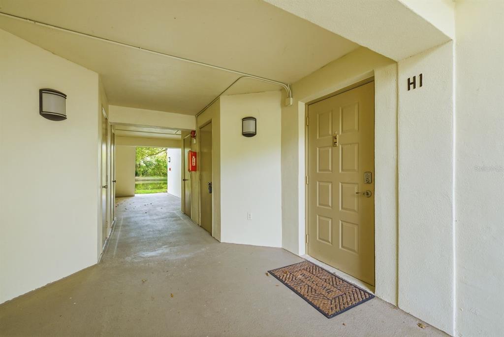 An exterior view of a tan apartment door labeled H1 with a welcome mat — 3134 LAKE PINE WAY UNIT H1, TARPON SPRINGS, FL