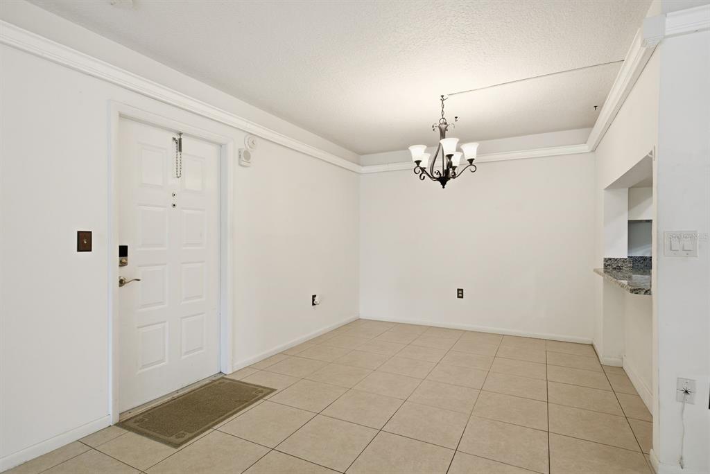A dining area with white walls, tile flooring, a chandelier, and a white entry door — 3134 LAKE PINE WAY UNIT H1, TARPON SPRINGS, FL
