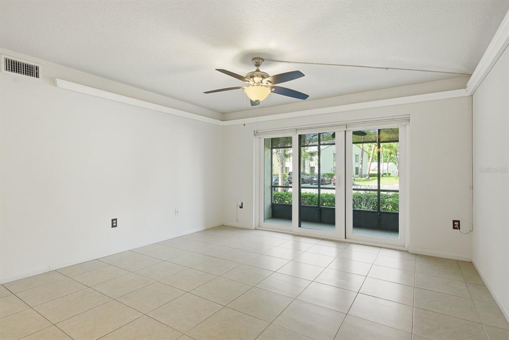 An empty room with light tile flooring, a ceiling fan, and sliding glass patio doors — 3134 LAKE PINE WAY UNIT H1, TARPON SPRINGS, FL