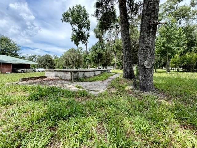 A concrete foundation sits in a grassy yard near a small building and large trees — 9749 FLORIDA STREET, FANNING SPRINGS, FL