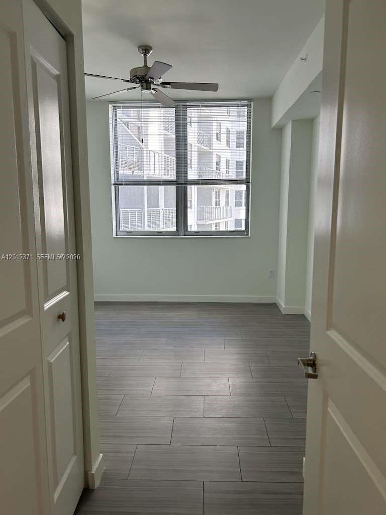 A bedroom with gray wood-look tile flooring, a ceiling fan, and a large window — 1776 Polk St # 505, Hollywood FL 33020, HOLLYWOOD, FL
