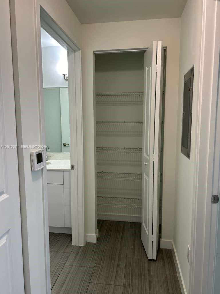 A hallway features a closet with wire shelving and an adjacent bathroom with a vanity — 1776 Polk St # 505, Hollywood FL 33020, HOLLYWOOD, FL