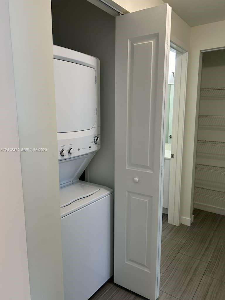 A stacked washer and dryer unit sits in a closet next to a pantry — 1776 Polk St # 505, Hollywood FL 33020, HOLLYWOOD, FL