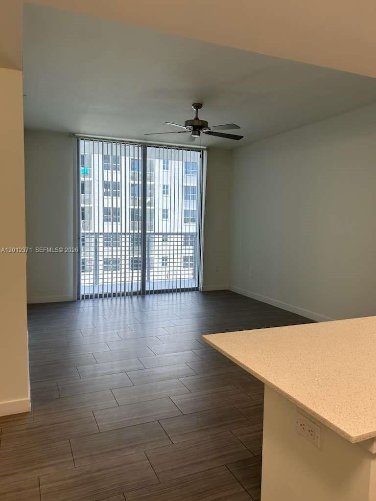 An empty room features wood-look tile flooring, a ceiling fan, and sliding glass balcony doors — 1776 Polk St # 505, Hollywood FL 33020, HOLLYWOOD, FL